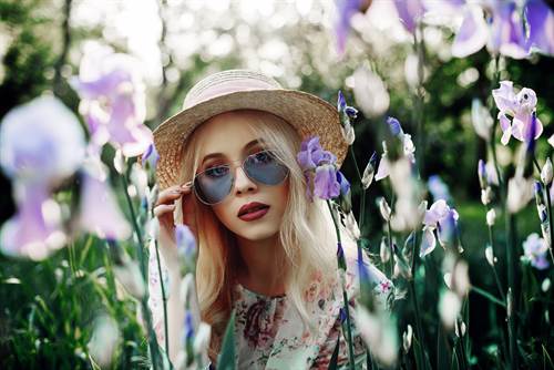 Frau mit Sonnenblume sitzt in einer Blumenwiese